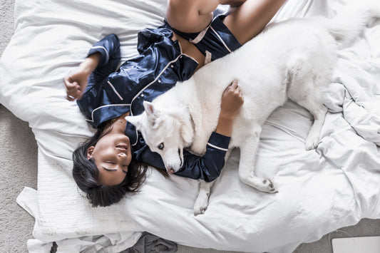 Woman sleeping in bed with her white dog